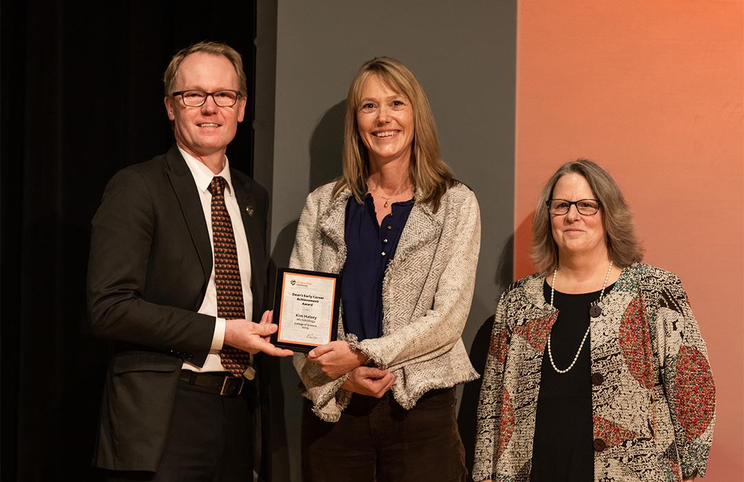 Kim Halsey receiving award from college on stage