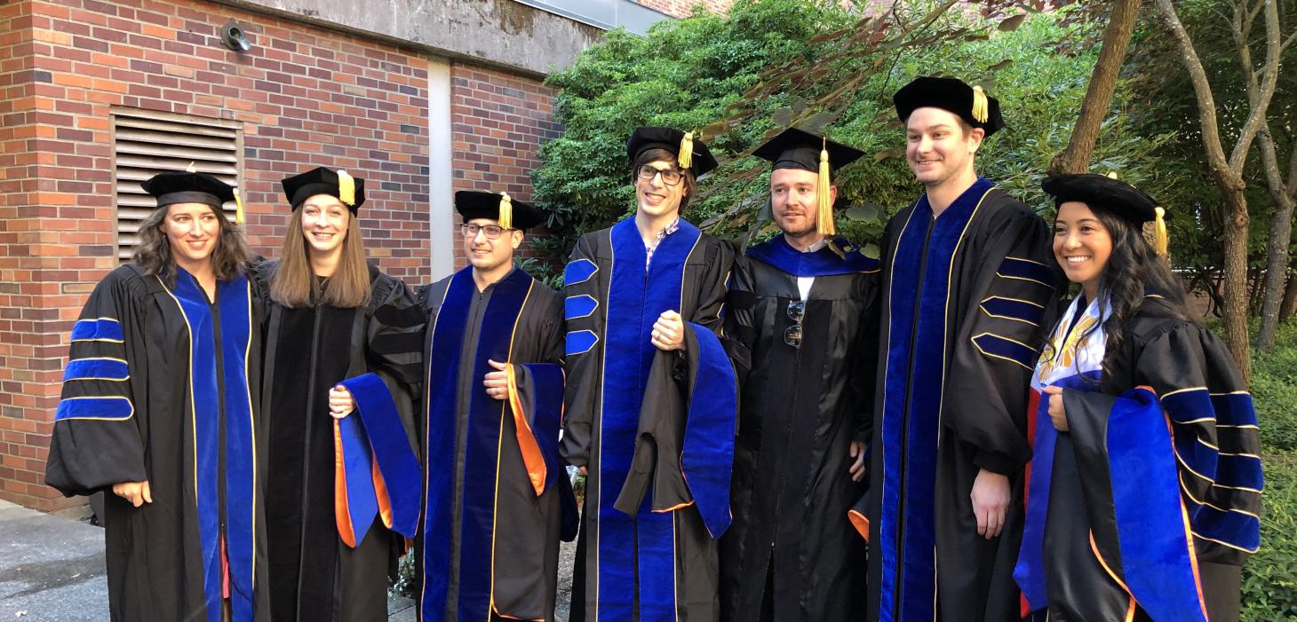 Seven IB graduate students in commencement regalia.