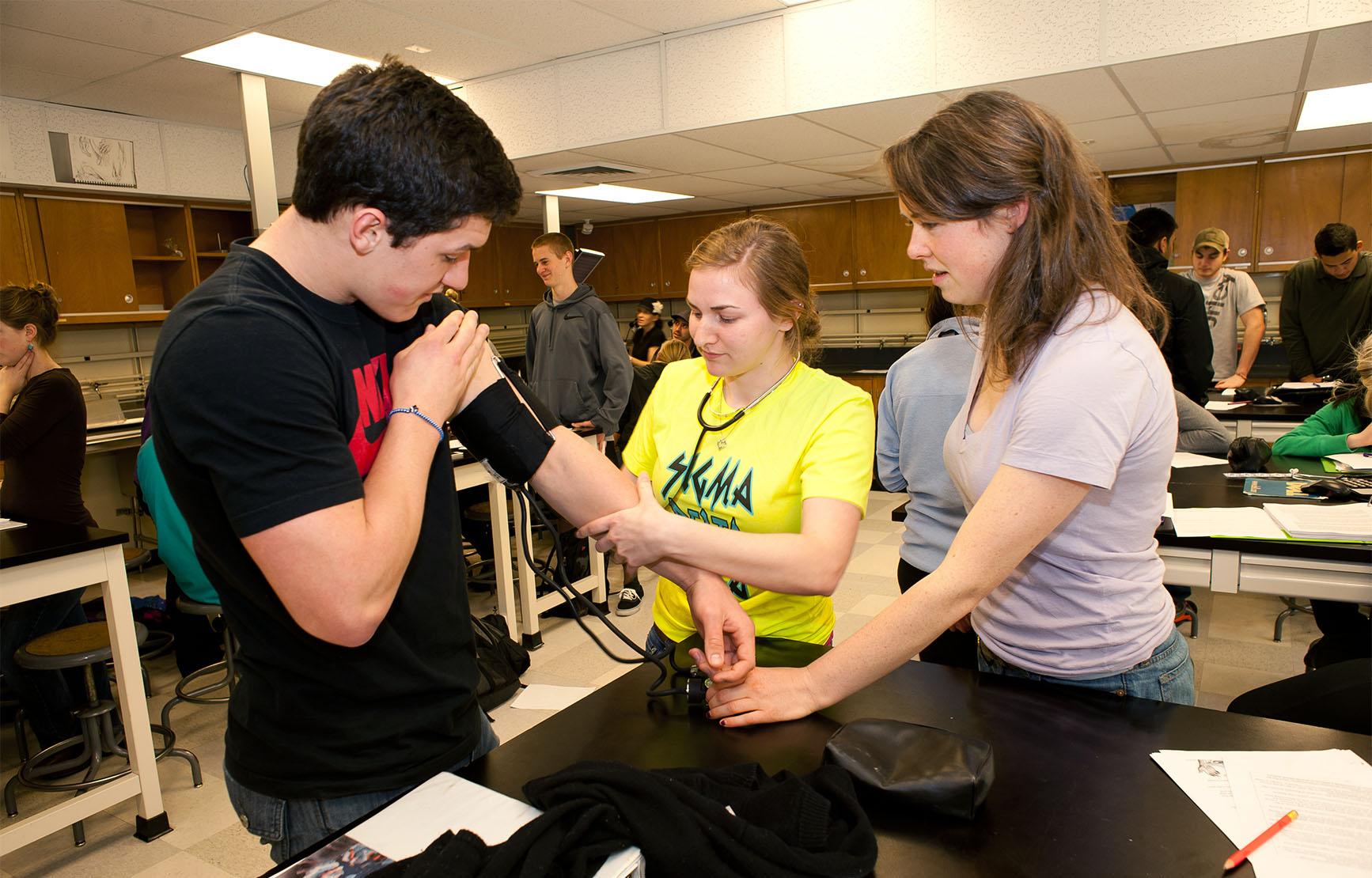 Students taking blood pressure measurement in anatomy class.