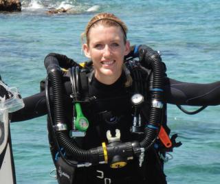 Megan Cook wearing scuba gear on the edge of a boat.